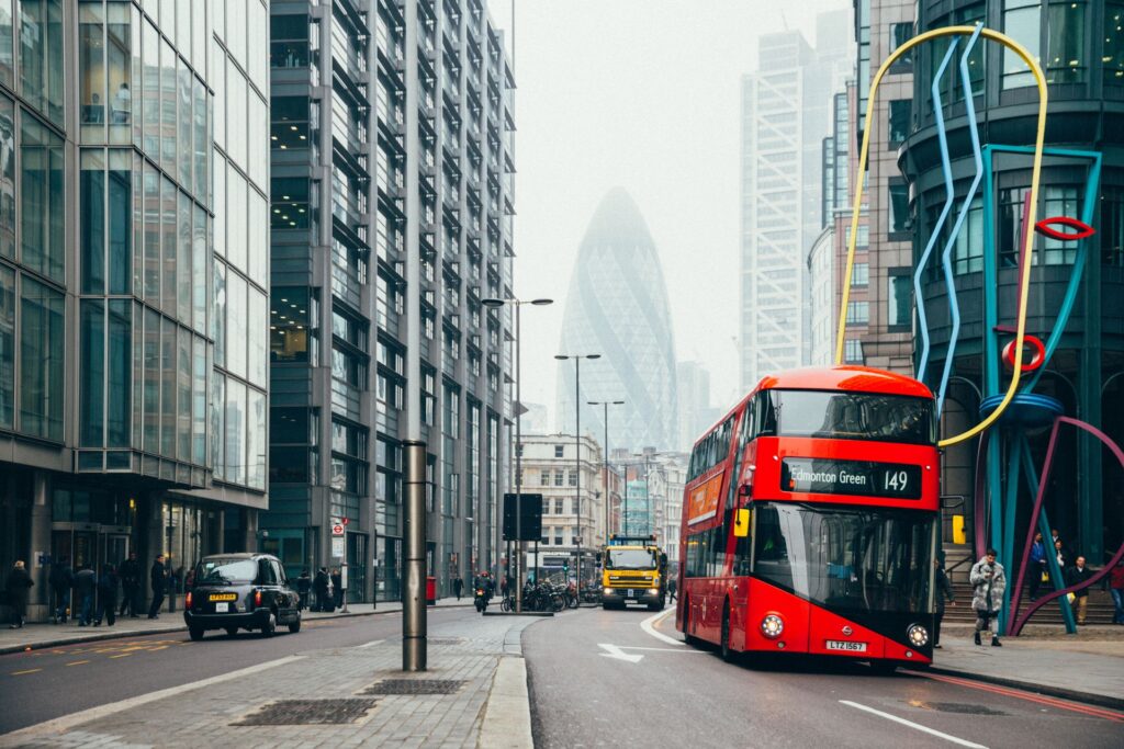 Red double decker bus on a London street with the Gherkin in the background
