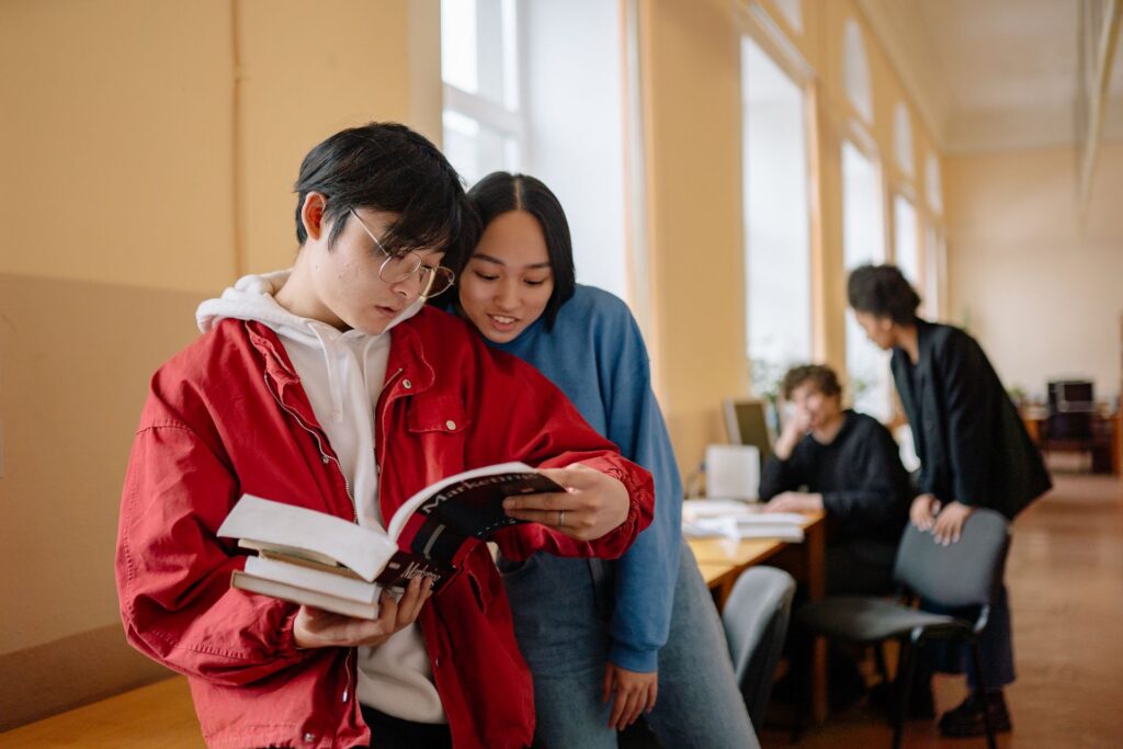 Two students reading a textbook together in a university building