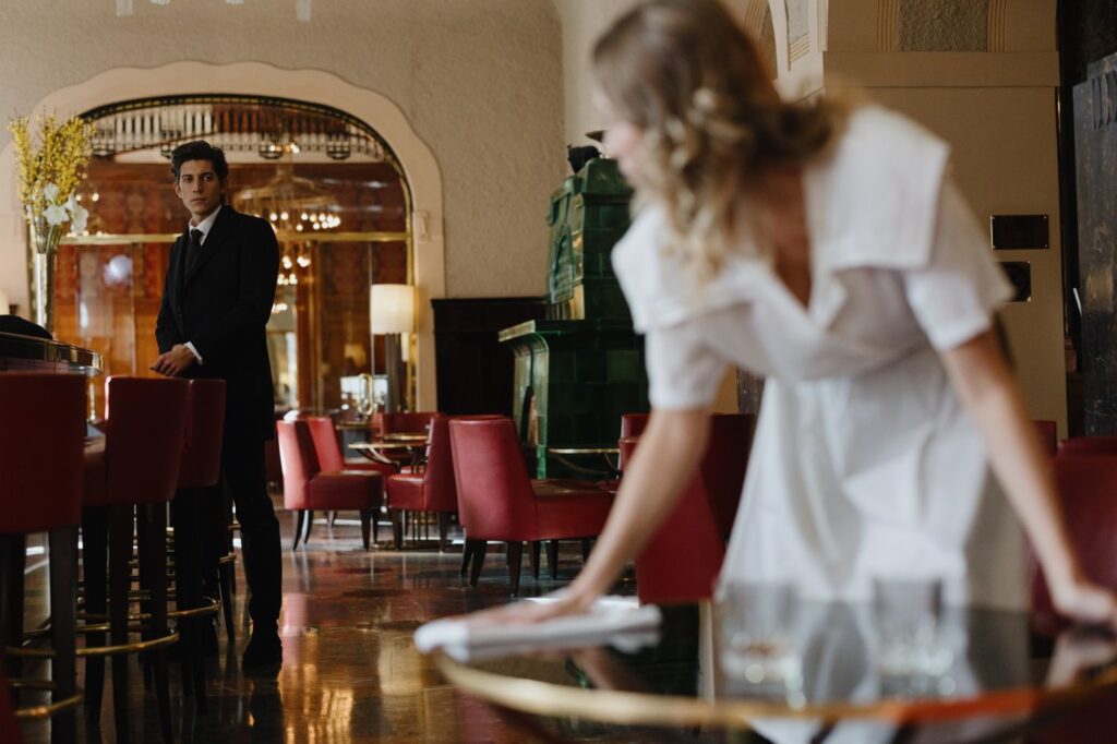 A waitress wipes down a table in a restaurant, one of the hospitality roles that hires in volume over the summer