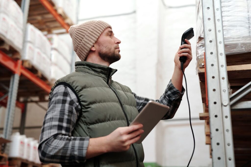 A warehouse worker checks stock with a handheld scanner, a common seasonal job in logistics
