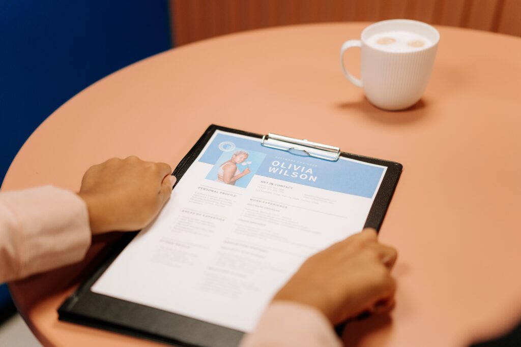 CV on a clipboard at a job interview table, its work experience section listing previous jobs