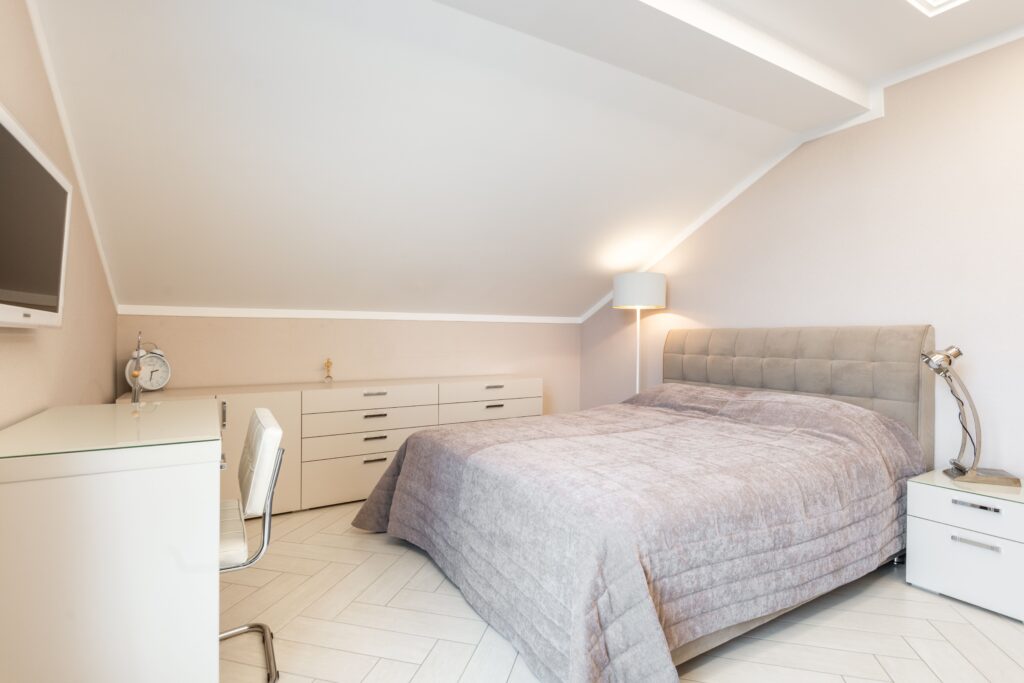 A tidy student bedroom with a desk and chair by a window