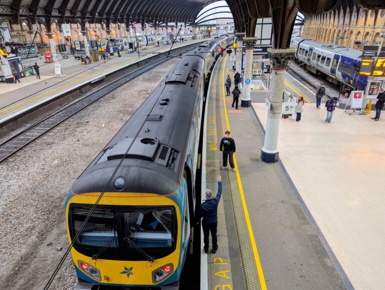 Overhead view of York train station with people on the platform and tr
