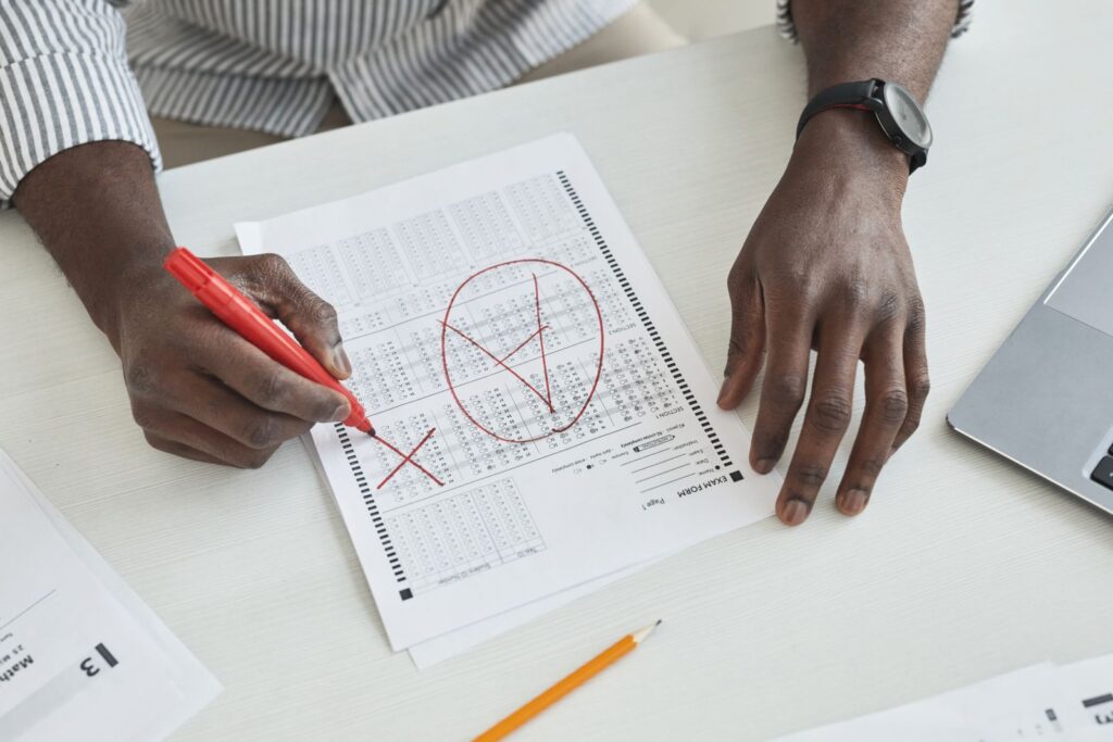An examiner marking an A-level answer sheet in red pen