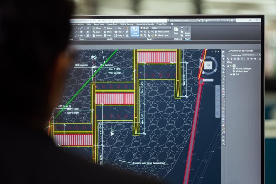 An AutoCAD structural drawing open on a large monitor in an engineering workspace