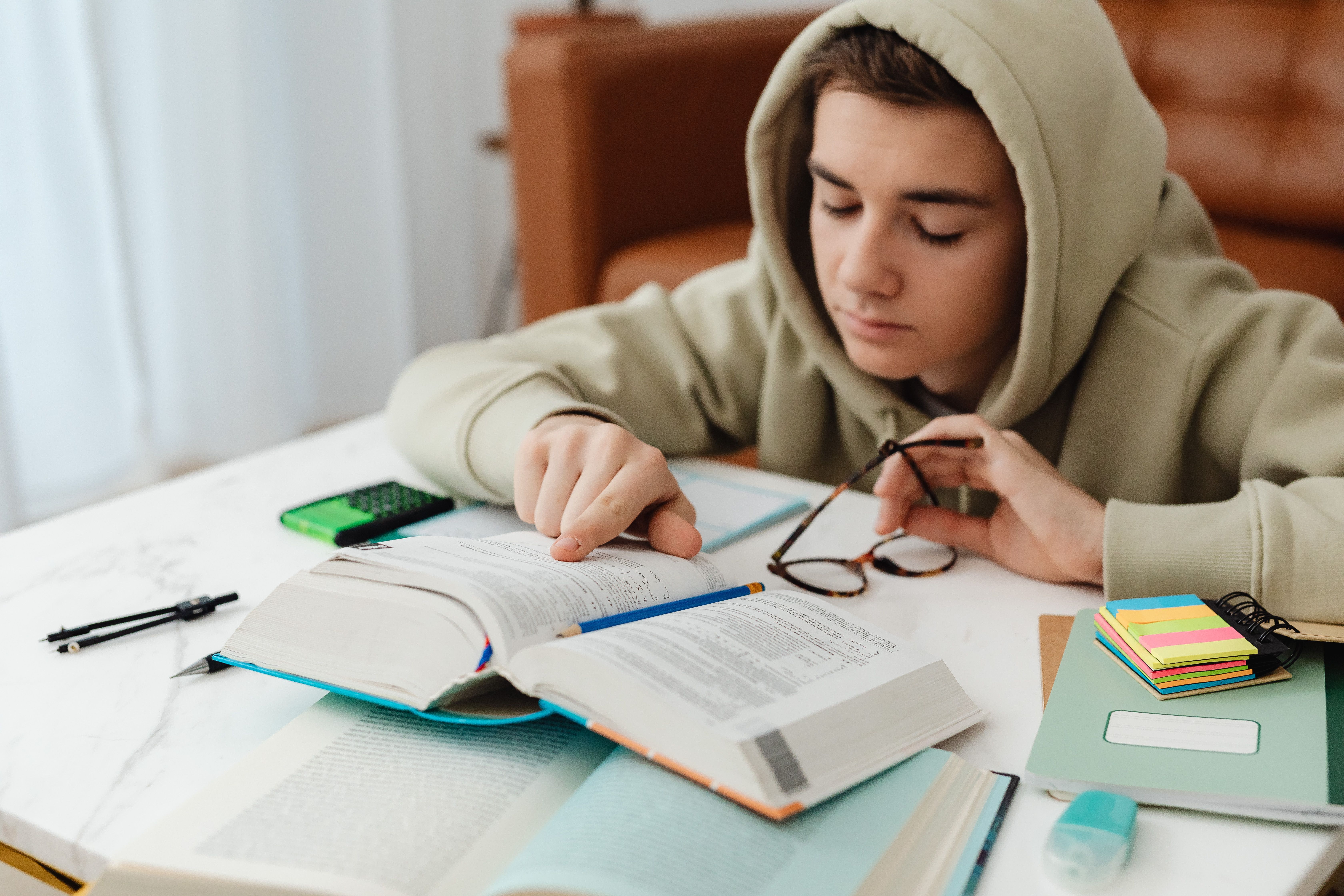 A teenager studying with a textbook, calculator and revision notes