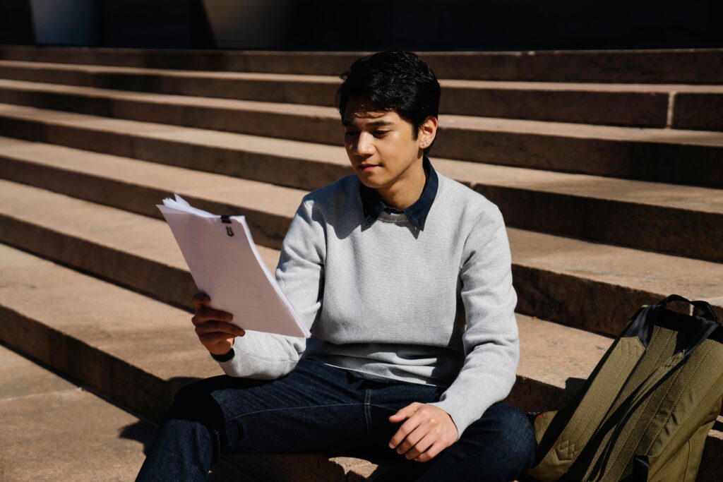 A student sitting on steps reading through their results and next steps