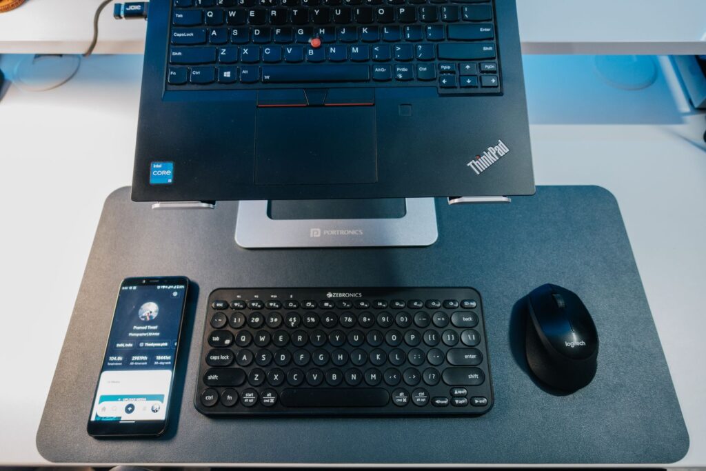 A refurbished ThinkPad laptop with an Intel Core i5 sticker on a desk stand beside a keyboard and mouse