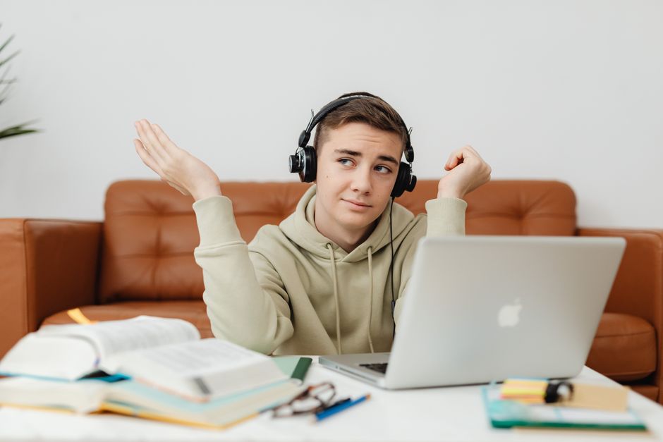 A student in headphones weighs something up at a laptop