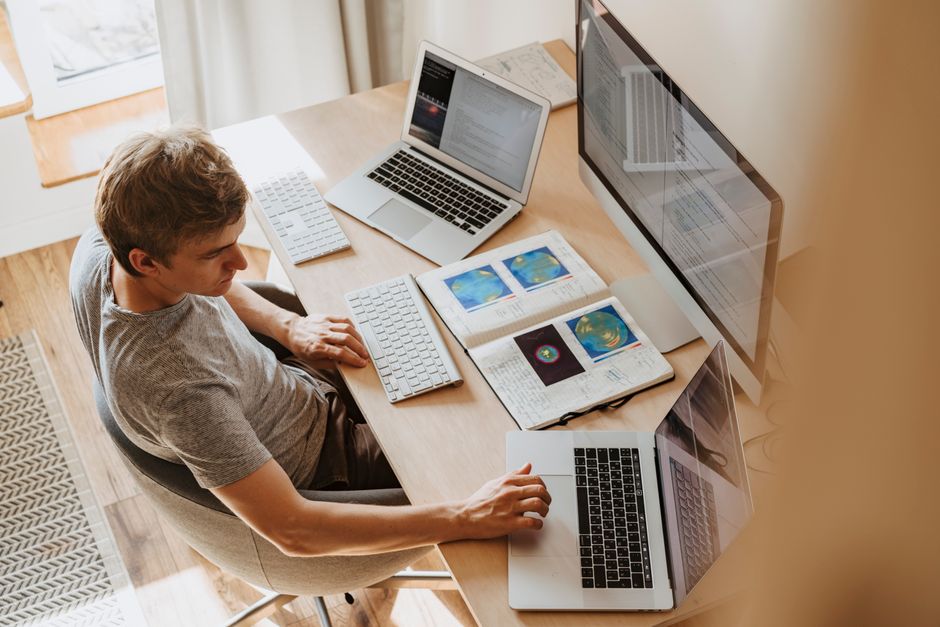 A student works across a laptop and an external monitor at a home desk