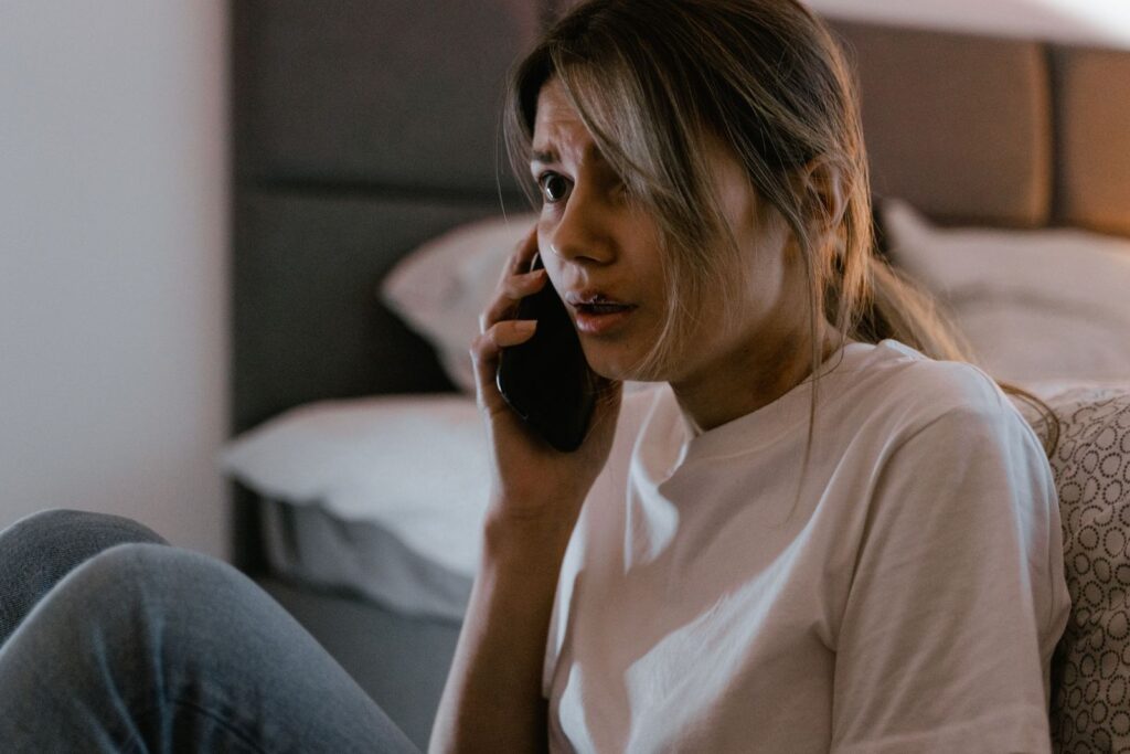 A student sits on a bed making a phone call on results day