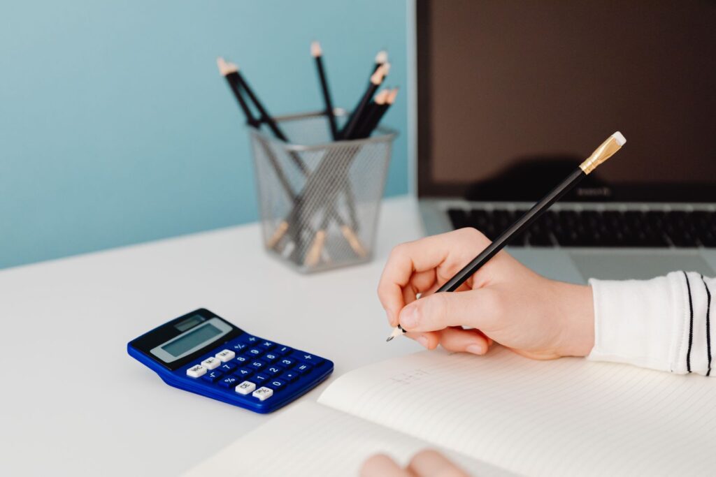 A student working out their raw exam mark with a calculator and notebook