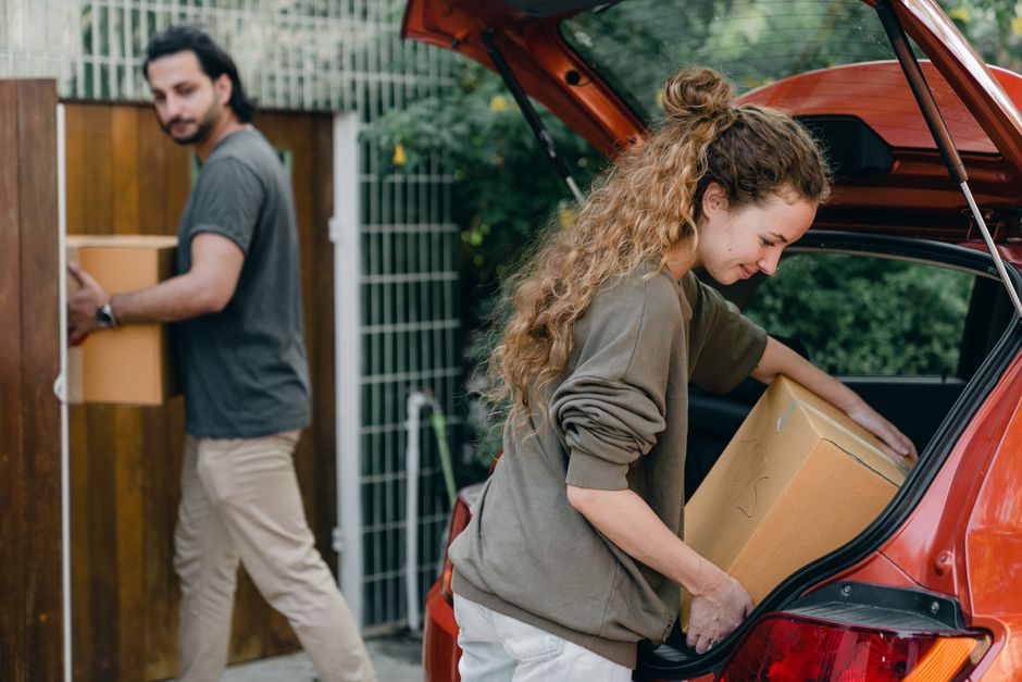 A student lifting a cardboard box from a car boot on moving-in day at university