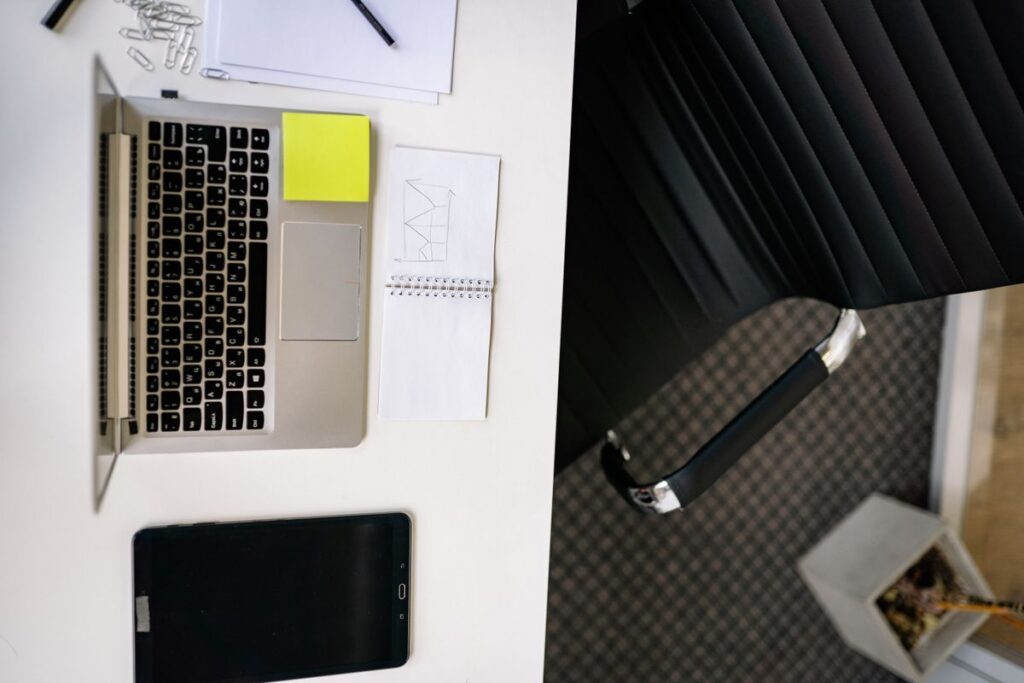 A laptop and a tablet on a student desk, the two devices students weigh up for note-taking