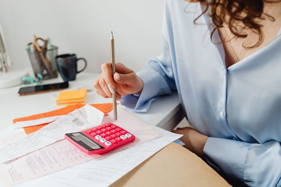 A student working out rent and loan payment dates with a calculator at a desk