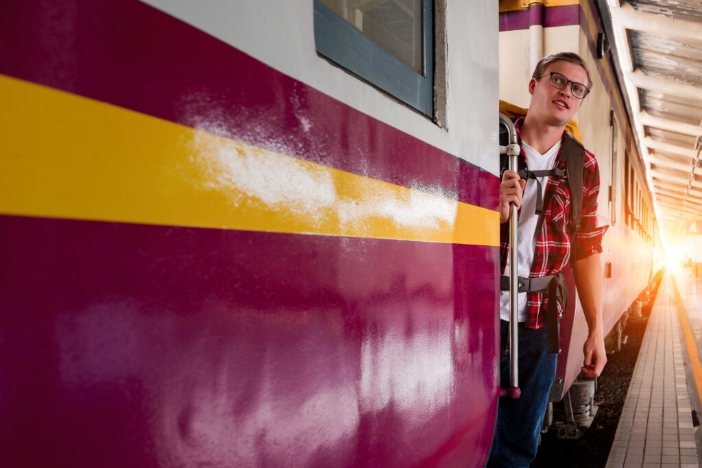 A young traveller with a backpack steps aboard a train at the platform
