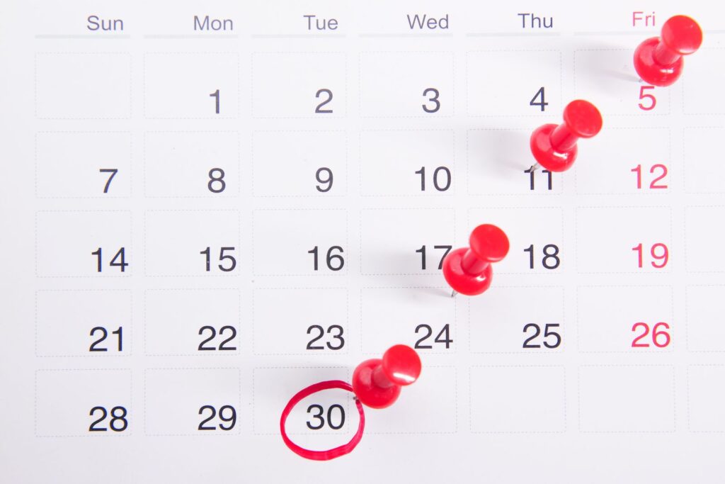 Calendar with red push pins marking dates, the deadlines that decide what dropping out costs on student finance